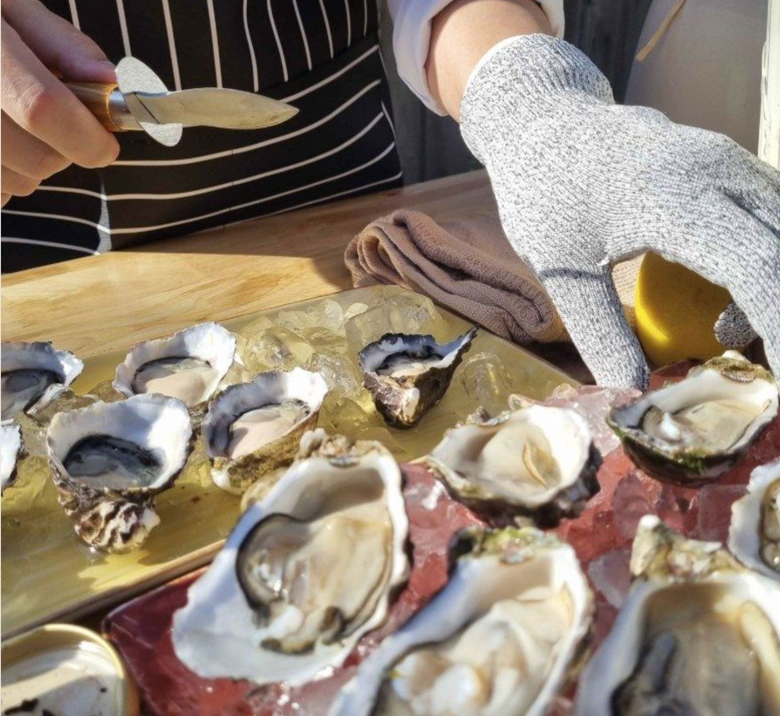 An oyster being shucked to order at the cart, with oysters resting on ice